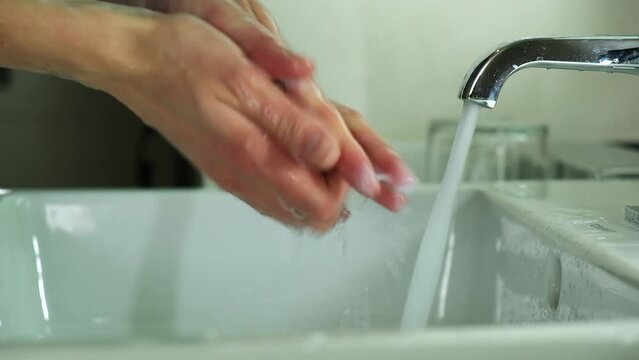 A girl in a blue medical suit washes hands. It soap with soap and carefully cleanses under the dda under the tap. Covid, Epivate. High quality FullHD footage