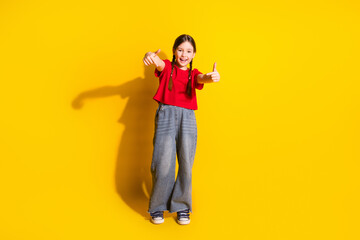 Full size photo of lovely small girl dance point fingers wear t-shirt isolated on yellow color background