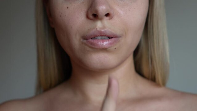 Silent gesture. Women's secret. Young caucasian blonde woman holding index finger on her mouth saying hush be quiet on a grey background