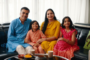 Portrait of happy Indian family sitting on sofa together at home