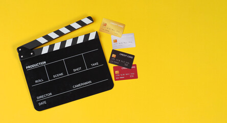 Clapper board with creit cards on yellow background.