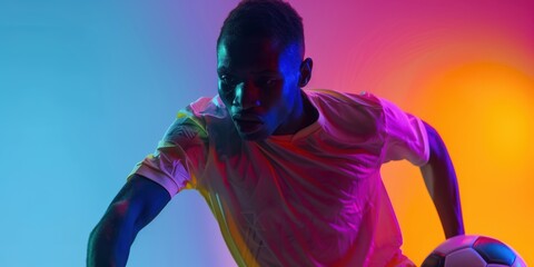 Male African American soccer and football player practicing alone against a gradient studio backdrop under neon lights. Idea of movement, activity, accomplishments