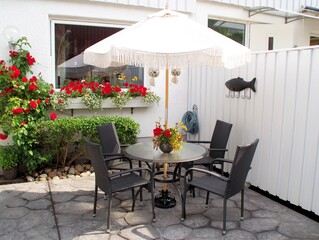 Porch with concrete pattern with table and chairs outside a house. Flower pot on the table.