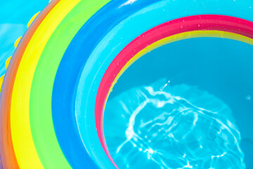Obraz premium Colorful rainbow inflatable ring in swimming pool, top view. Shot for design. Summer vacation concept. Hotel spa resort advertisement. Beach and water toys