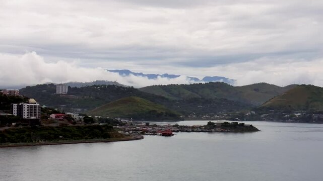 Walter Bay rainy cloudy fog layer morning sunrise Ela Beach Port Moresby Papua New Guinea aerial drone PNG gray cloudy Coral sea coastline capital city hotels mountains circle right motion