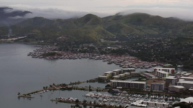 Morning cloudy foggy sunrise Port Moresby Harbour Ela Beach Papua New Guinea aerial drone PNG Walter Bay rainy Coral sea coastline capital city Crown Hotel Plaza Hilton mountains backwards motion