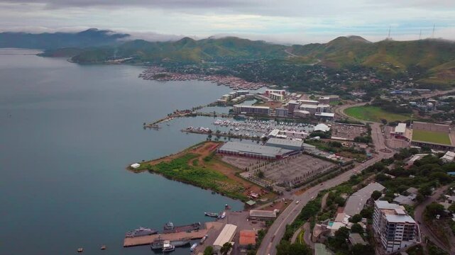 Port Moresby Harbour Marina car traffic Papua New Guinea aerial drone morning cloudy foggy sunrise PNG Crown Hotel Plaza Hilton Ela Beach Walter Bay Coral Sea coastline capital city backwards pan up