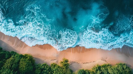 Aerial view of ocean waves crashing on a sandy beach with lush green trees