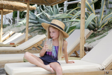 Cute little girl holding a glass full of fresh made lemonade, summer refreshing drink, healthy...