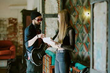 Medium long shot of male and female rock musicians standing in living room of abandoned house...