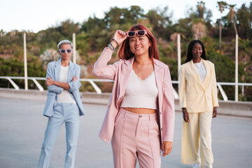 Naklejka premium Group of businesswomen in cheerful colorful suits outdoors. Concept: feminism, empowerment