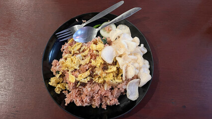 Nasi goreng jawa or javanese fried rice chicken with vegetable and crackers on white plate. Indonesian food Asian cuisine. Nasi Goreng is an Indonesian cuisine dish with jasmine rice, chicken meat