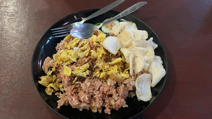 Nasi goreng jawa or javanese fried rice chicken with vegetable and crackers on white plate. Indonesian food Asian cuisine. Nasi Goreng is an Indonesian cuisine dish with jasmine rice, chicken meat