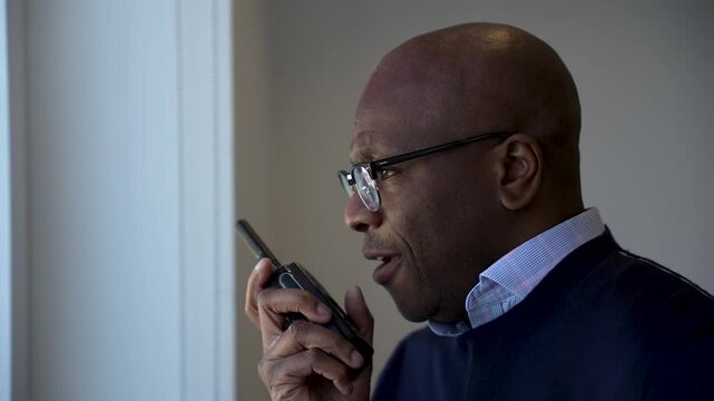 Smiling businessman communicating through a walkie talkie in a modern office setting. Professional and focused interaction. Close Up Shot
