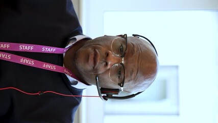 Staff member in a call center provides customer service with a headset, phone, and lanyard badge, showcasing communication and professionalism. vertical video - Powered by Adobe