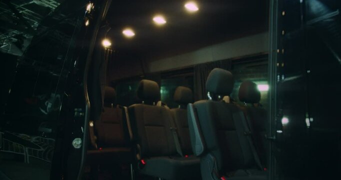 Beautiful slow motion, 4k shot of a van with the door open with its wide, clean seats. Parked in a large dark warehouse.