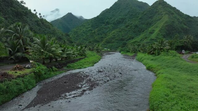 Teahupoo River Tahiti French Polynesia aerial drone mountains morning grey gray raining fog season wet green grass end of the road Point Faremahora village town buildings island forward pan reveal