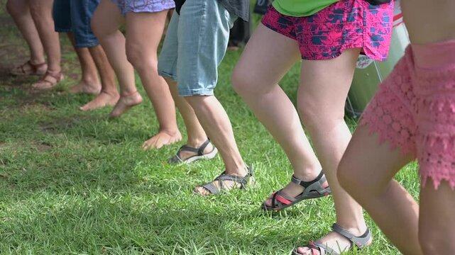 Legs of a group of people dancing at the same time on the grass