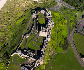 erial Bamburgh Castle. Bamburgh Castle, on the northeast coast of England, by the village of Bamburgh in Northumberland, is a Grade I listed building.