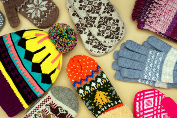 Clothes for the cold seasons in the form of mittens and hats. Mittens, gloves and a hat create the background. Warm clothes for autumn and winter.