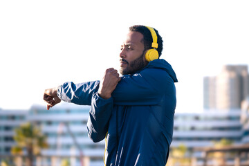 Active and fit male runner in warm-up stretch for running or cardio exercise.
