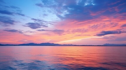 Fototapeta premium This image features a calm ocean beneath a colorful sunset sky dotted with clouds, where the warm hues of pink, purple, and blue create a tranquil and picturesque scene.