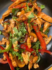 Fajitas Chicken meat, sliced bell pepper, and parsley in a frying pan.