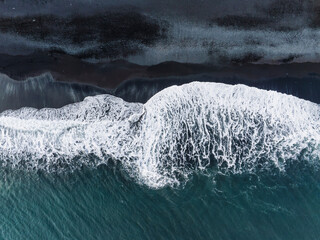 Stunning aerial shot capturing the contrast of black sand and white waves on an Icelandic beach....
