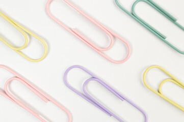 Top view of colorful paperclips on white background. School, office wallpaper. Flat lay, copy space.