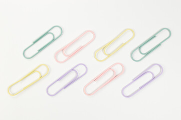 Top view of colorful paperclips on white background. School, office wallpaper. Flat lay, copy space.