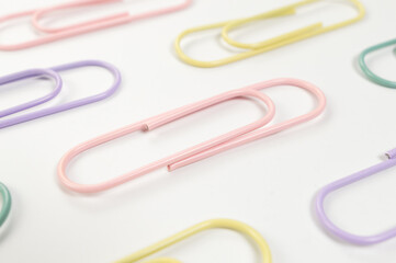 Top view of colorful paperclips on white background. School, office wallpaper. Flat lay, copy space.