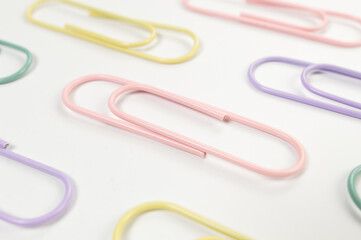 Top view of colorful paperclips on white background. School, office wallpaper. Flat lay, copy space.