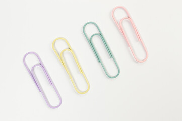 Top view of colorful paperclips on white background. School, office wallpaper. Flat lay, copy space.