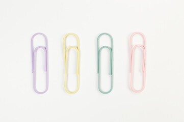 Top view of colorful paperclips on white background. School, office wallpaper. Flat lay, copy space.