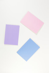 Top view of pink, purple and blue notebooks on white background. School, office wallpaper. Flat lay, copy space.
