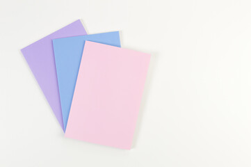 Top view of pink, purple and blue notebooks on white background. School, office wallpaper. Flat lay, copy space.