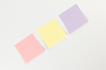 Top view of colorful sticky notes on white background. School, office wallpaper. Flat lay, copy space.