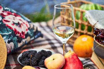 picnic in nature with fruit and wine on the river bank on a summer day 