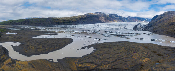 A stunning aerial view of a light blue glacial lake in Iceland, surrounded by black volcanic rock...