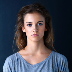 Naklejka premium Portrait, girl and studio with serious, pose and confidence in dark background for fashion or style. Female teenager, gen z and model with isolated, wellness or skincare for beauty, hair care or glow