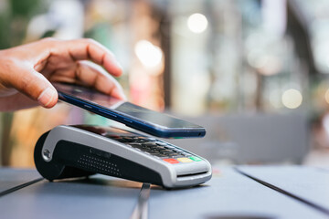 man paying contactless with mobile phone in restaurant.