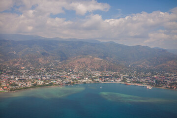 Aerial view of Dili City, the capital of Timor Leste. Urban settlements with a beach in the foreground and hills in the background.