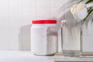 Collagen protein powder with glass of water on white kitchen table. Natural supplement for beauty, health of skin, bones, joints and intestines, anti-age concept