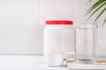 Collagen protein powder with glass of water on white kitchen table. Natural supplement for beauty, health of skin, bones, joints and intestines, anti-age concept