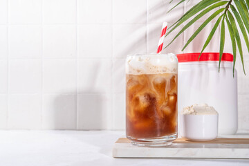 Collagen latte coffee drink glass with collagen powder in jar and spoon, on white kitchen table. Natural supplement for beauty, health of skin, bones, joints and intestines, anti-age concept