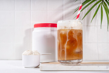 Collagen latte coffee drink glass with collagen powder in jar and spoon, on white kitchen table....