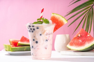 Watermelon boba balls bubble tea cocktail. Refreshing milky non-dairy milkshake cocktail with boba balls and watermelon slices on background. Summer garnished sweet dessert iced drink 