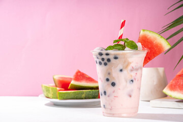 Watermelon boba balls bubble tea cocktail. Refreshing milky non-dairy milkshake cocktail with boba balls and watermelon slices on background. Summer garnished sweet dessert iced drink 