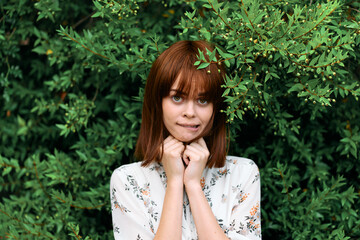 Serene redhead woman striking a thoughtful pose among lush greenery and trees