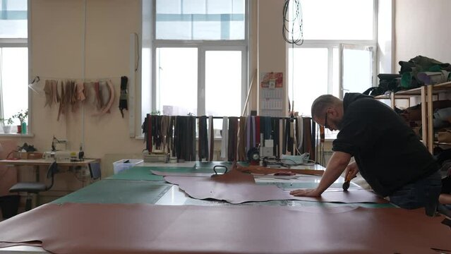 Caucasian bearded man working as a tanner in a workshop. 